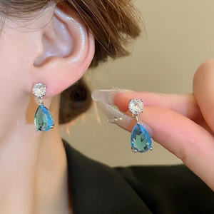 Detailed view of silver water drop earrings with blue zircon stones on a female model