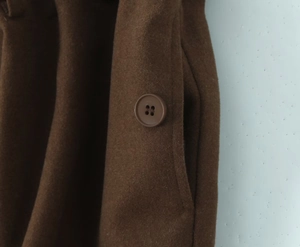 Vue macro du tissu marron en laine mélangée avec un bouton à quatre trous assorti