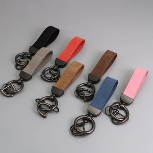 Flat lay of seven colorful suede leather keychains with dark metal rings on grey background
