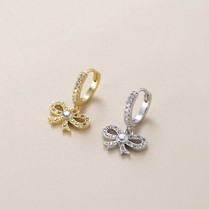 Close-up of gold and silver bow earrings with micro-pave cubic zirconia crystals