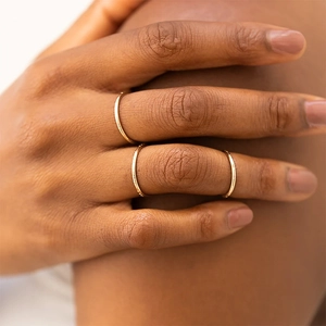 Close-up of three minimalist thin gold stacking rings worn on a model's hand