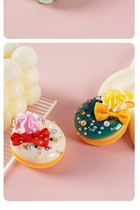 Detailed close-up of handmade faux donut charms with cream, bows and pearls