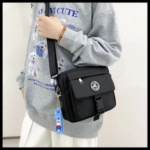 Detail of black nylon crossbody bag with PINBO logo buckle and blue rocket charm