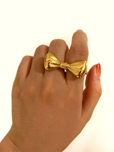 Vue rapprochée d'une grande bague nœud dorée avec finition polie sur une main