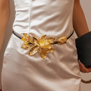 Détail de la boucle fleur tulipe dorée 3D sur une ceinture fine en cuir noir pour femme