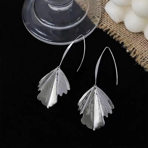 Macro shot of silver metal leaf earrings with radial texture on a premium dark background