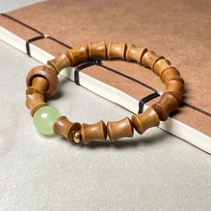 Bracelet en bois de santal style bambou avec perle de jade verte sur un carnet