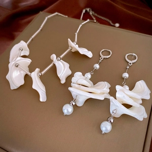 Détail de boucles d'oreilles à perles et collier vintage sur un tissu en soie marron
