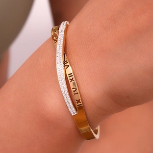 Detail shot of a gold-plated crisscross bangle with Roman numerals and micro-pave zircons