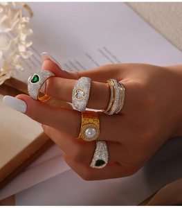 Detailed view of hand wearing luxury gold and silver rings with pearls and green gemstones