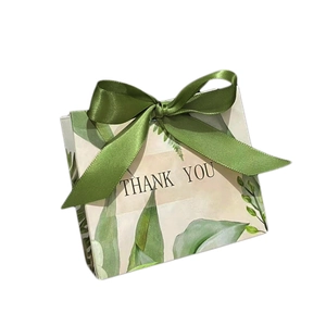 Elegant white wedding favor box with green botanical leaves and a satin ribbon bow