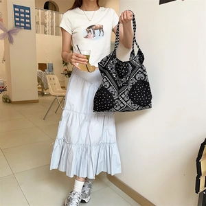 Detail view of large canvas tote bag with black paisley print and woven brand label