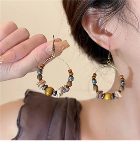 Macro detail of bohemian hoop earrings with vintage beads and natural shell dangles