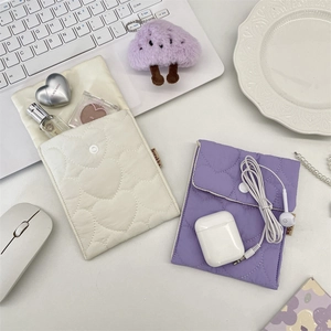 Close-up of quilted heart pattern and snap button on cream and purple storage pouches