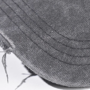 Macro detail of dark grey baseball cap showing parallel stitching and distressed brim edge