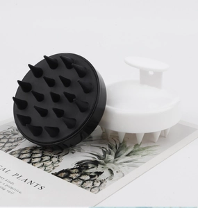 Close-up of black and white silicone scalp massage brushes with ergonomic finger grips