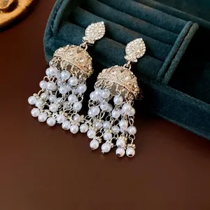 Elegant silver tassel earrings with pearls and crystals on a green velvet jewelry box