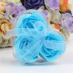 Detail of three blue rose-shaped soap flowers in a heart-shaped gift box with a blue ribbon