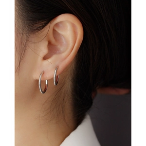 Detail showing polished silver S925 earrings on a model with a double piercing look
