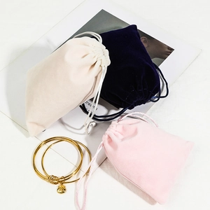 Elegant velvet drawstring jewelry pouches in beige, navy, and pink with gold bracelets