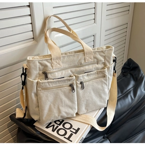 Detail view of corduroy tote bag with dual front pockets and adjustable shoulder strap