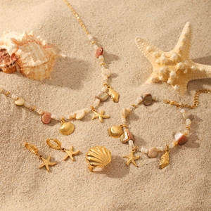 Golden sea-themed jewelry set with starfish pendants on sand, including necklace and rings