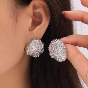 Irregular textured silver stud earrings with vintage floral carving worn by model