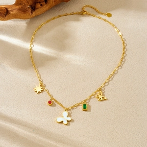 Gold necklace featuring butterfly star and gemstone pendants on textured beige background