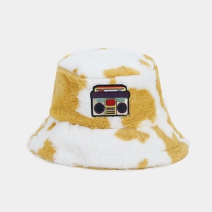 Detail view of plush cow print bucket hat with retro cassette tape embroidered patch