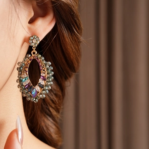 Gros plan de boucles d'oreilles bohèmes ovales dorées avec cristaux sur un mannequin