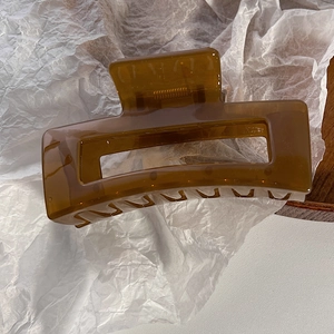 Dettaglio di una grande molletta per capelli quadrata ambra in resina trasparente cava