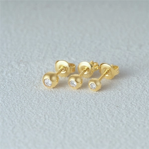 Macro shot of gold silver ball earrings set with sparkling round cubic zirconia stones