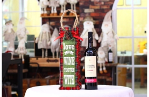 Detailed view of red plaid Christmas wine bag with pine cones and festive bow ornament