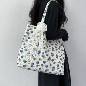 Blueberry print canvas tote bag with white lace bow decoration shown on shoulder
