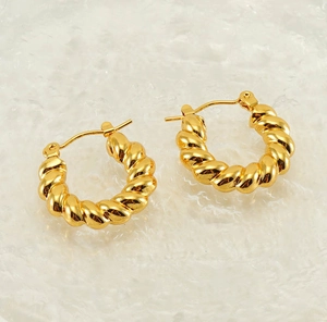 Close-up of golden croissant hoop earrings featuring intricate twisted rope texture detail