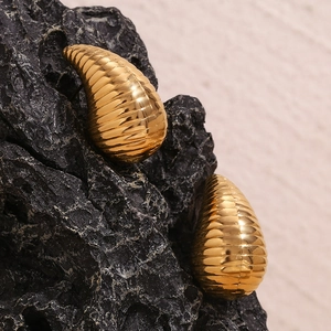 Macro view of 18K gold plated hollow teardrop earrings with textured horizontal stripes