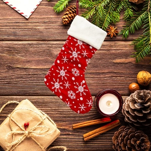 Red Christmas stocking with white snowflake patterns on a festive wooden tabletop setup