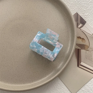Dettaglio di molletta per capelli quadrata con motivo marmorizzato blu rosa in ceramica