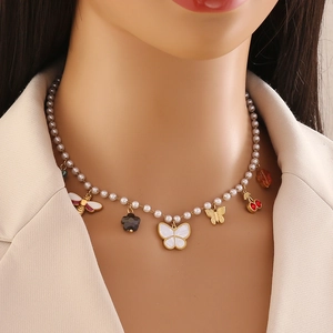 Collier de perles dorées avec breloques papillon, abeille et cerise sur modèle