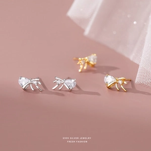 Detailed view of silver and gold bow earrings made of S999 sterling silver with white zircon