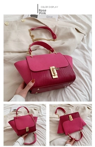 Detail of rose pink handbag featuring crocodile embossing and gold chain strap