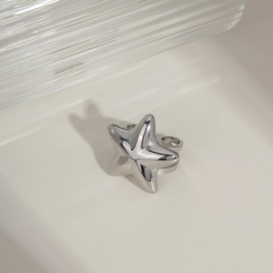 Detailed view of a silver star-shaped ring made of polished stainless steel on a textured base