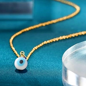 Detailed close-up of blue evil eye charm pendant on a golden stainless steel chain