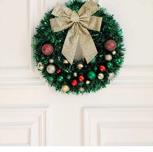 Detail of a 45cm Christmas wreath with red ornaments and a gold bow on a white door