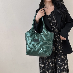 Borsa tote trapuntata verde scuro con finitura lucida indossata da una modella