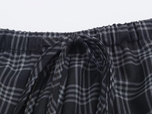 Detail of elastic waistband and adjustable drawstring on black and grey plaid shorts