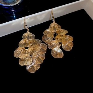 Detailed close-up of golden hollow petal fringe earrings with layered metallic texture