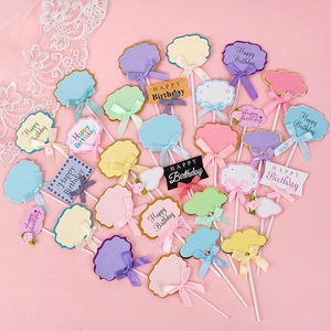 Blank Happy Birthday cake toppers with bows in various colors and shapes on pink background