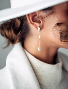 Detail of elegant asymmetric baroque pearl earrings with irregular gold surface on model