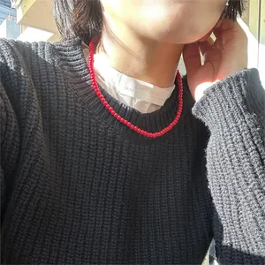 Vista dettagliata di una collana minimalista con perline rosse vivaci su un maglione